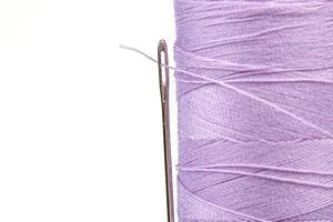macro madeja de hilo púrpura colores con un aguja en un blanco antecedentes foto