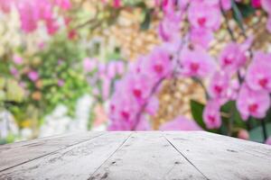 Empty wood table top with blur orchid garden background for product display photo