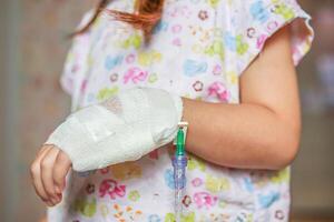 cerca arriba niño mano con salina iv solución en hospital foto