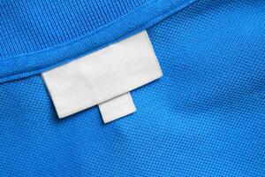 Blank white laundry care clothes label on blue shirt fabric texture background photo