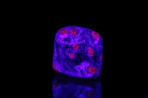 macro mineral stone ruby under ultraviolet light on a black background photo