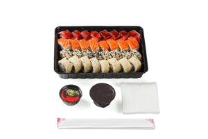 un conjunto de Sushi en un entrega caja, soja salsa, palillos, wasabi, jengibre en un blanco antecedentes foto