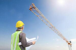 construction engineer worker in protective helmet and blueprints paper on hand at building site background photo