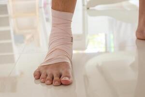 Man with ankle sprain elastic bandage for ankle injury and feeling pain photo