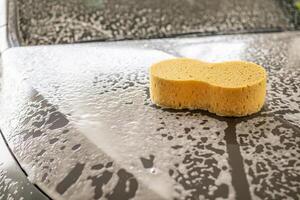 coche limpieza y Lavado con amarillo esponja y espuma jabón foto