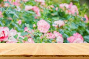 vacío madera mesa parte superior con difuminar Rosa jardín antecedentes para producto monitor foto