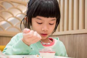 linda pequeño asiático niño niña comiendo comida foto