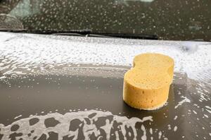 coche limpieza y Lavado con amarillo esponja y espuma jabón foto