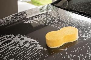 car cleaning and washing with yellow sponge and foam soap photo