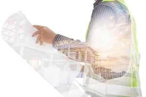 Double exposure image of professional engineer in protective helmet and blueprints paper at building construction site photo