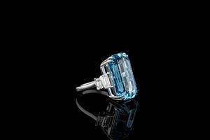 Beautiful gold ring with aquamarine and diamonds on a black background photo