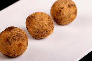 Beautiful candy truffle on a white plate on a black background photo