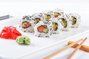 Sushi with salmon on a white plate with wasabi, ginger, soy, chopsticks on a white background photo