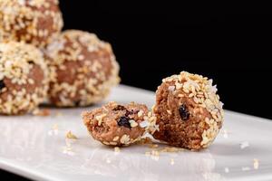 Beautiful candies with sesame seeds on a white plate on a black background photo