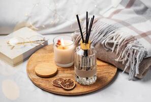 Home fragrance in glass bottle and bamboo sticks with scented candle,  paper book. photo