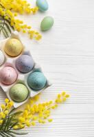 Colorful easter eggs  and mimosa flowers on wooden table. photo