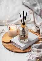 Home fragrance in glass bottle and bamboo sticks with scented candle,  paper book. photo