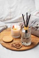 Home fragrance in glass bottle and bamboo sticks with scented candle,  paper book. photo