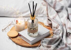 Home fragrance in glass bottle and bamboo sticks with scented candle,  paper book. photo