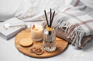 Home fragrance in glass bottle and bamboo sticks with scented candle,  paper book. photo