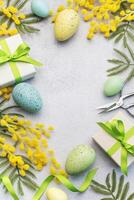 Mimosa branch, Easter eggs and gift boxes on gray concrete background. photo