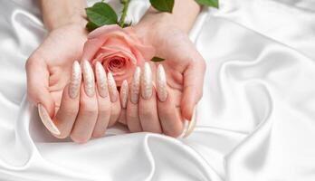 hembra manos en un blanco seda antecedentes con hermosa perla manicura foto