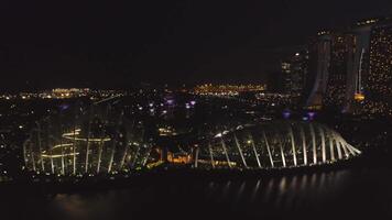 Singapur - 25 septiembre 2018. Singapur rascacielos edificio a centro de deportes acuáticos bahía playa a noche con hermosa luces de grande noche ciudad. disparo. panorama de Singapur horizonte y río a noche. video