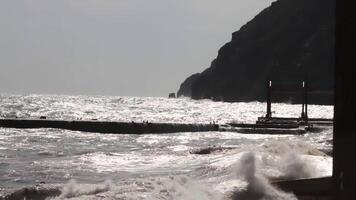 mare onda e molo a tramonto con sole raggi. sparo. tramonto, tempesta su il mare, frangiflutti. tramonto, il sole in partenza nel il mare onde. ghiaia a partire dal ciottolo. il sole va al di là il orizzonte. onda spruzzo su molo video