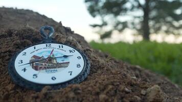 White vintage wall clock lying on the ground, land. Footage. Wall clock or watch lying on the ground tree background. Wall clock old rusty grunge on stone wall background video