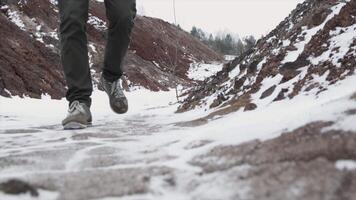 avvicinamento di maschio gambe nel inverno scarpe a piedi su neve. filmato, Visualizza di a piedi su neve con neve scarpe e scarpa picchi nel inverno. Uomini gambe nel stivali vicino su il innevato sentiero video