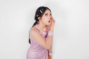 A young beautiful Asian woman is shouting and screaming loud with a hand on her mouth, isolated by white background. photo