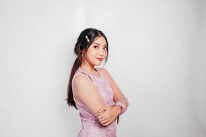 An attractive Asian woman wearing pink dress is smiling to the camera, isolated by white background. photo