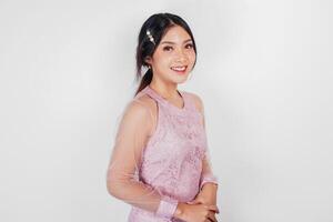 An attractive Asian woman wearing pink dress is smiling to the camera, isolated by white background. photo