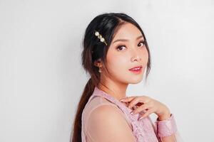 An attractive Asian woman wearing pink dress is smiling to the camera, isolated by white background. photo