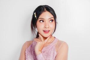 An attractive Asian woman wearing pink dress is smiling to the camera, isolated by white background. photo