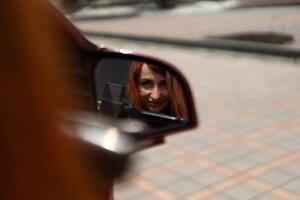 reflexión de un mujer en un coche lado ver espejo. un mujer reflexión en el lado ver espejo de un coche foto