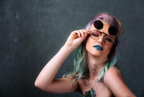A Woman with Vibrant Hair and Stylish Eyewear. A woman with blue and green hair wearing glasses photo