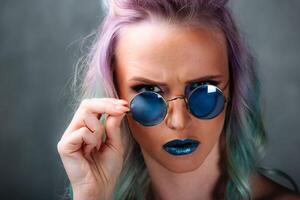 vibrante mujer con púrpura pelo y azul lentes. un mujer con púrpura pelo y azul lentes foto