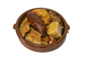 A clay bowl with pringa,mixed meat, chorizo, bacon, chicken, pork loin, from a chickpea stew, isolated on a white background. Spanish food concept. photo