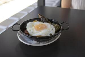 A tapa of fried potatoes, fried egg, chistorra and fried green pepper. Spanish food concept. photo