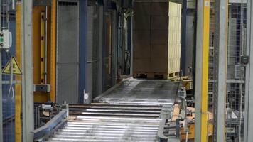 Shipping box in motion on conveyor belt, end of the line. Clip. Moving conveyor belt with cardboard boxes along corridor in workplace. Carboard boxes travelling on a conveyor belt in a factory video