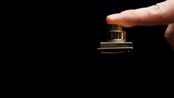 Perfume bottle with male finger on black background. Man applying Perfume. Man's Perfume in the Hand on Black Background. Hand with spray bottle on a dark background video