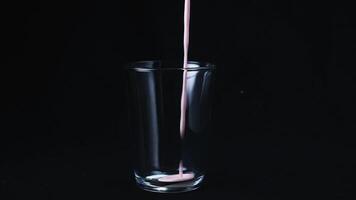 Close-up of fresh strawberry milk shake and strawberry fallen in the glass. Frame. Black background video