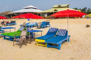 colorful wooden beach umbrellas and sunbeds loungers on sandy beach of ocean photo
