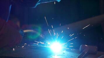 Worker with protective mask welding metal. A man welds a metal with a welding machine. Welder is working at the factory and welding a metal construction. Welders working at the factory made metal video