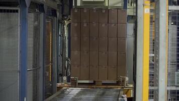 Shipping box in motion on conveyor belt, end of the line. Clip. Moving conveyor belt with cardboard boxes along corridor in workplace. Carboard boxes travelling on a conveyor belt in a factory video