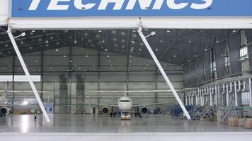 Roller shutter door and concrete floor of airport hangar and airplane background. Airport hangar from the outside with big tall doors. Front view. Aircraft Hangar video