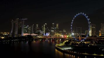 Singapour - 25 septembre 2018. Singapour ville horizon à nuit avec le rivière, violet éclairé ferris roue et célèbre Marina baie sables Hôtel. tir. Stupéfiant aérien vue de nuit Singapour avec video