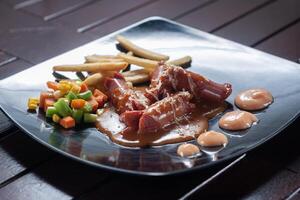 barbecue sauce sausage steak on black plate photo