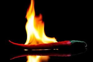 rojo chiles ardiente en llamas en un negro vaso mesa foto
